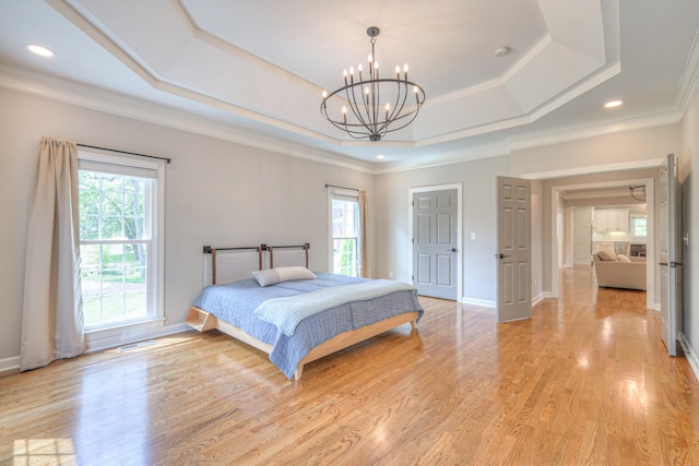 bedroom with a raised ceiling, multiple windows, light wood finished floors, and a notable chandelier