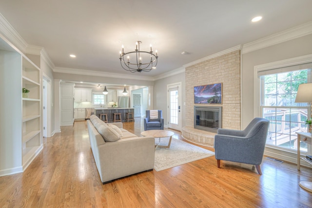 living room featuring visible vents, a fireplace, recessed lighting, light wood finished floors, and a notable chandelier