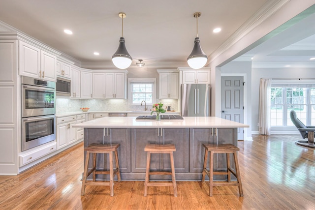 kitchen with light countertops, a kitchen island, white cabinets, and stainless steel appliances