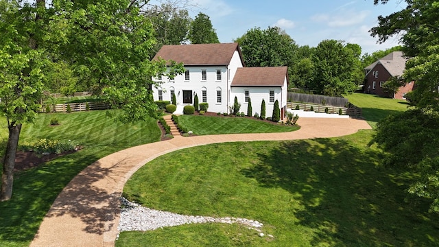 view of front of property with a shingled roof, fence, and a front yard
