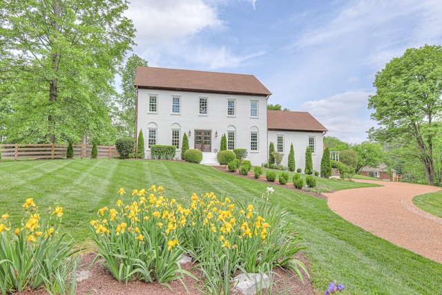 colonial-style house featuring fence and a front yard