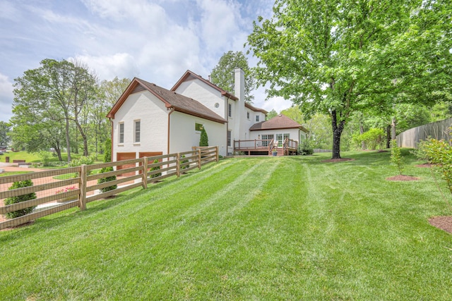 back of property with a lawn, a fenced backyard, a chimney, and a deck