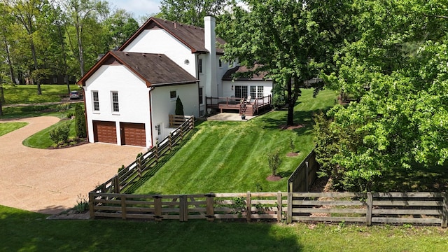 view of property exterior with fence, a wooden deck, stucco siding, a yard, and driveway
