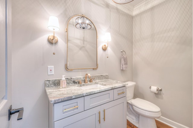 bathroom featuring crown molding, vanity, toilet, baseboards, and wood finished floors