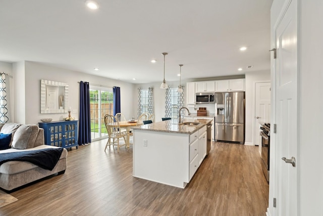 kitchen with recessed lighting, white cabinets, light stone counters, a sink, and stainless steel appliances
