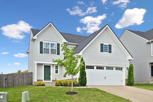 traditional-style home featuring a garage, fence, driveway, and a front lawn