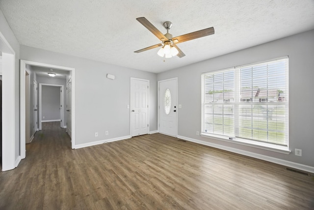 interior space featuring a ceiling fan, baseboards, a textured ceiling, and dark wood-type flooring