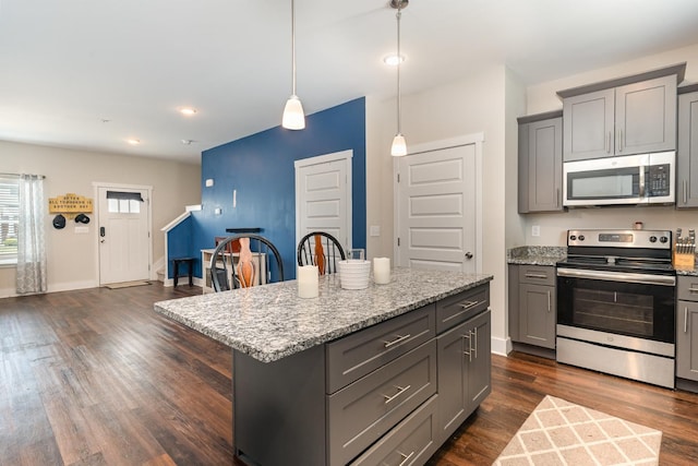 7025 Magnolia Crossings, Spring Hill, TN 37174 - kitchen featuring gray cabinets, dark wood-style floors, light stone countertops, a kitchen island, and appliances with stainless steel finishes