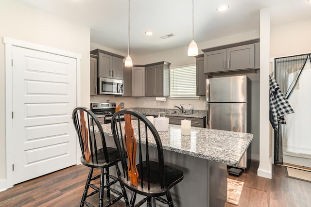 7025 Magnolia Crossings, Spring Hill, TN 37174 - kitchen featuring a breakfast bar area, stainless steel appliances, gray cabinets, visible vents, and light stone counters