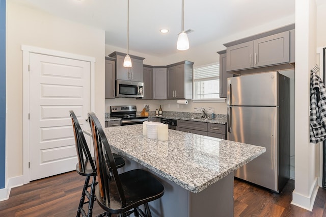 7025 Magnolia Crossings, Spring Hill, TN 37174 - kitchen with appliances with stainless steel finishes, gray cabinets, light stone counters, a kitchen island, and dark wood-style flooring