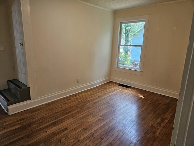 spare room with baseboards, ornamental molding, dark wood-style flooring, and visible vents