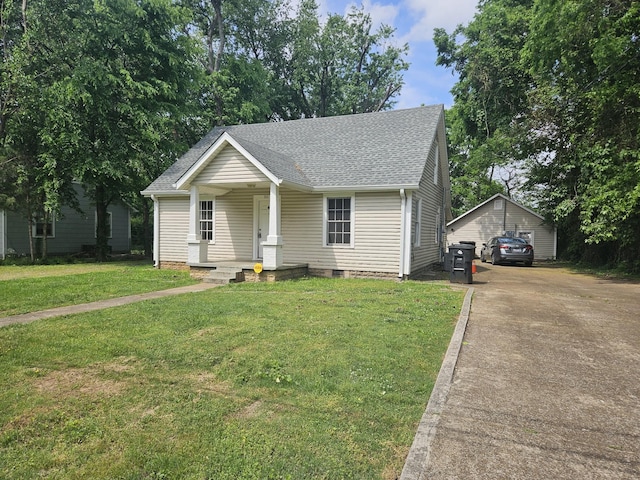 view of front of home with covered porch, crawl space, a front yard, a detached garage, and a shingled roof