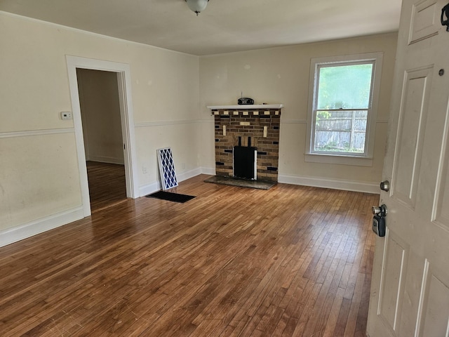 unfurnished living room featuring baseboards, hardwood / wood-style flooring, and a fireplace