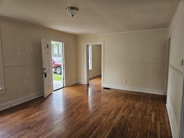 spare room with wood-type flooring, crown molding, and baseboards