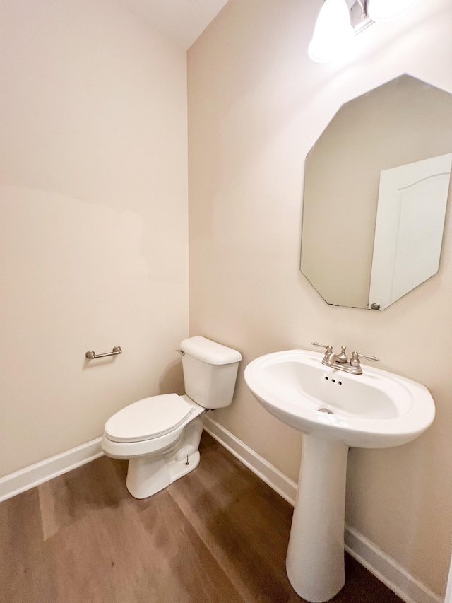 bathroom featuring a sink, baseboards, toilet, and wood finished floors