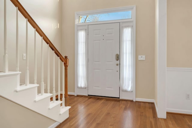 entryway with baseboards, stairs, and wood finished floors