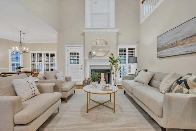 living area with a towering ceiling, wood finished floors, a chandelier, and a fireplace
