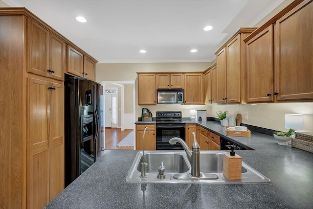 kitchen featuring recessed lighting, a sink, black appliances, and dark countertops