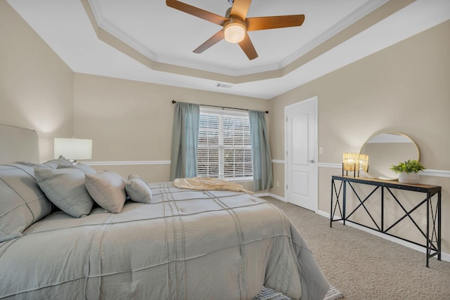 carpeted bedroom with visible vents, ornamental molding, baseboards, ceiling fan, and a tray ceiling