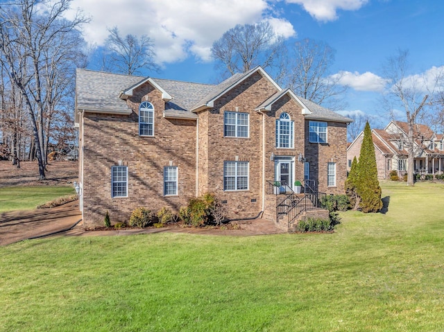 view of front of house featuring brick siding, a shingled roof, and a front yard