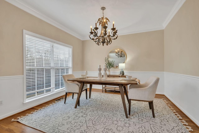dining area with an inviting chandelier, crown molding, and wood finished floors