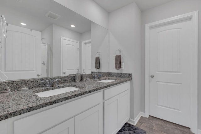 bathroom with double vanity, a sink, baseboards, and recessed lighting