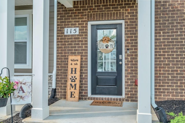 property entrance featuring covered porch and brick siding