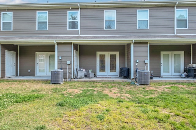 rear view of house with a lawn, a patio, central AC unit, and french doors