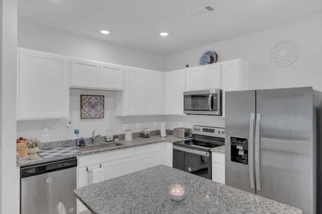 kitchen with a sink, appliances with stainless steel finishes, white cabinetry, and visible vents