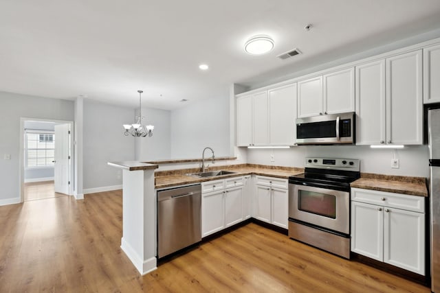 8231 Lenox Creekside Dr Unit C7, Antioch, TN 37013 - kitchen with appliances with stainless steel finishes, a sink, white cabinetry, a peninsula, and a chandelier