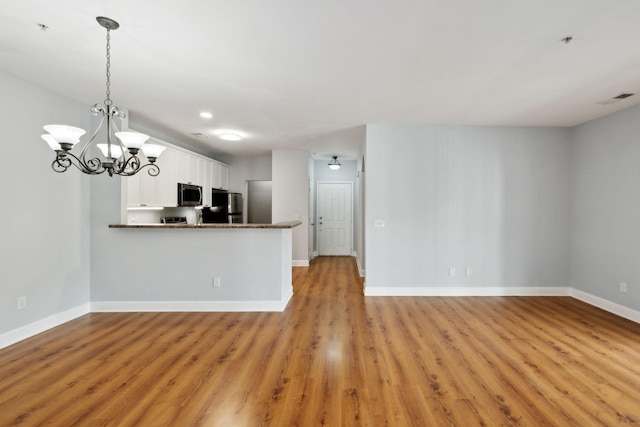 8231 Lenox Creekside Dr Unit C7, Antioch, TN 37013 - kitchen with appliances with stainless steel finishes, white cabinets, light wood finished floors, baseboards, and a chandelier