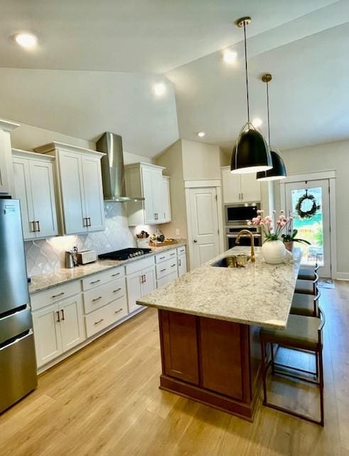 113 Cryer Dr, Gallatin, TN 37066 - kitchen featuring light wood-type flooring, wall chimney exhaust hood, white cabinetry, a sink, and appliances with stainless steel finishes