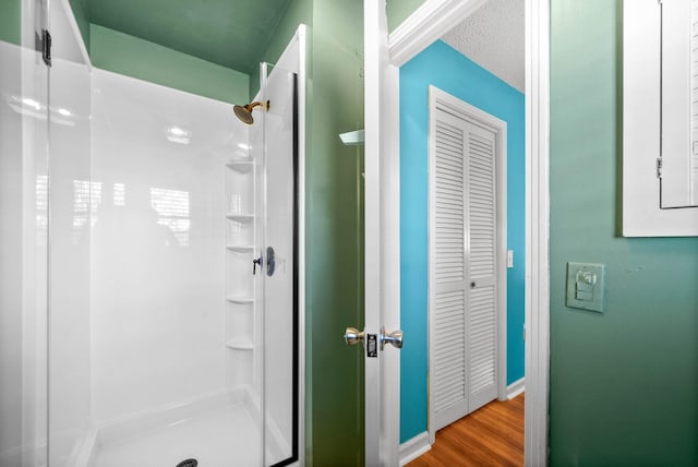 bathroom featuring baseboards, wood finished floors, and a stall shower