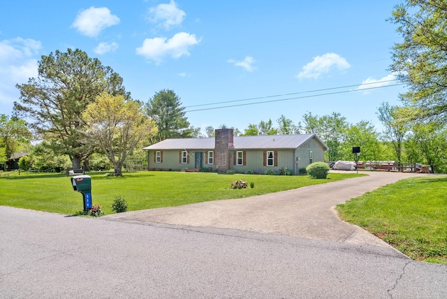 single story home with a chimney, a front lawn, and aphalt driveway