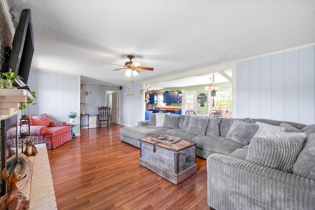 living room featuring a textured ceiling, ceiling fan with notable chandelier, and wood finished floors