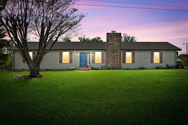 ranch-style house with board and batten siding, a chimney, metal roof, and a front yard