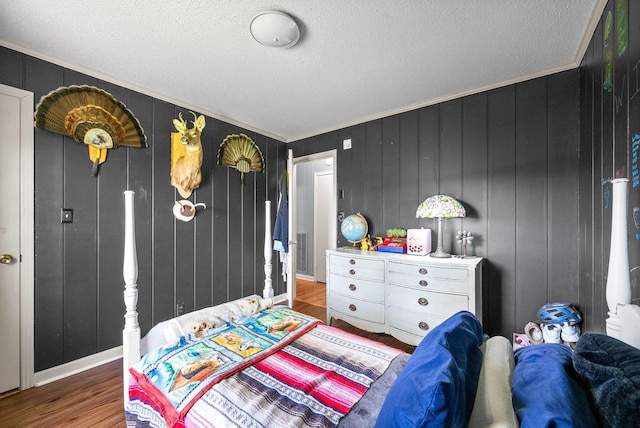 bedroom featuring crown molding, a textured ceiling, and wood finished floors