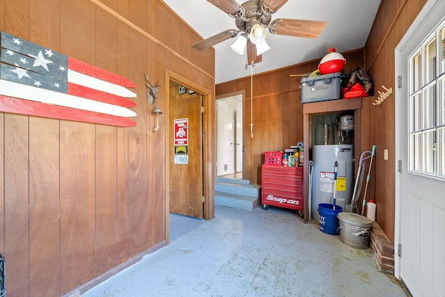 garage with ceiling fan, wooden walls, and electric water heater