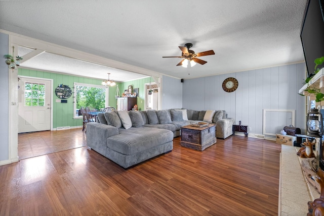 living area with a textured ceiling, ornamental molding, ceiling fan with notable chandelier, and wood finished floors