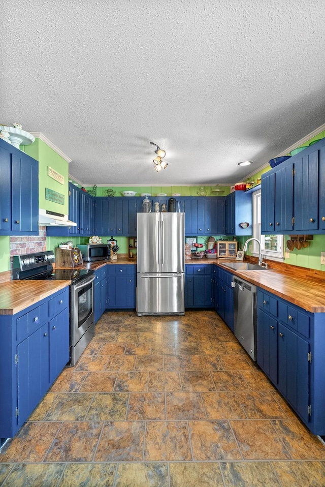 kitchen featuring butcher block countertops, a textured ceiling, stainless steel appliances, a sink, and blue cabinetry