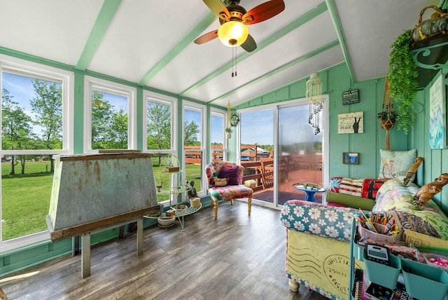 sunroom featuring a healthy amount of sunlight, lofted ceiling with beams, and wood finished floors