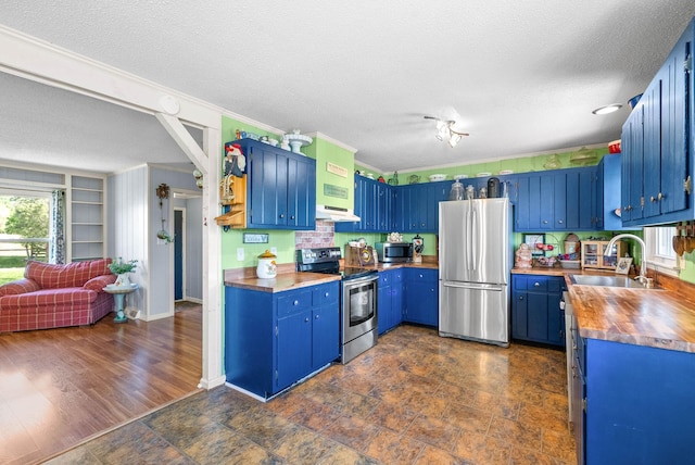 kitchen featuring under cabinet range hood, stainless steel appliances, a textured ceiling, and a sink