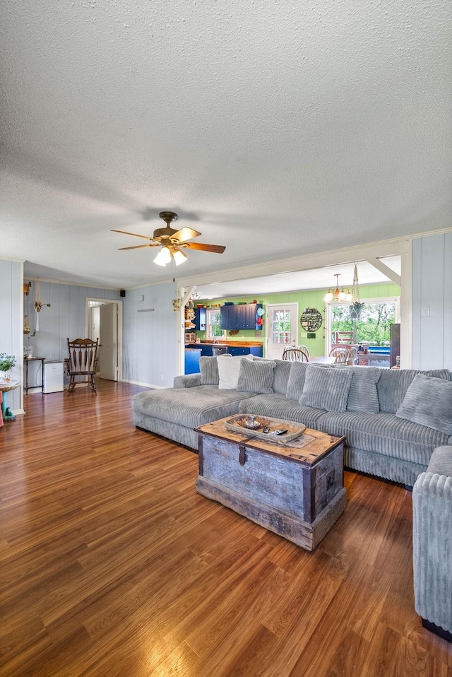living area with a textured ceiling, wood finished floors, and ceiling fan with notable chandelier