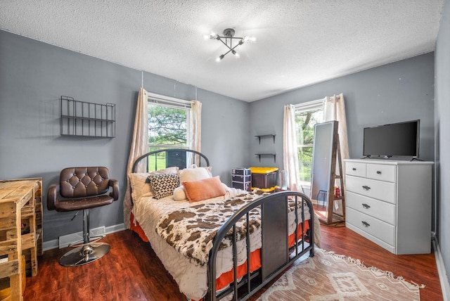 bedroom with baseboards, a textured ceiling, and wood finished floors