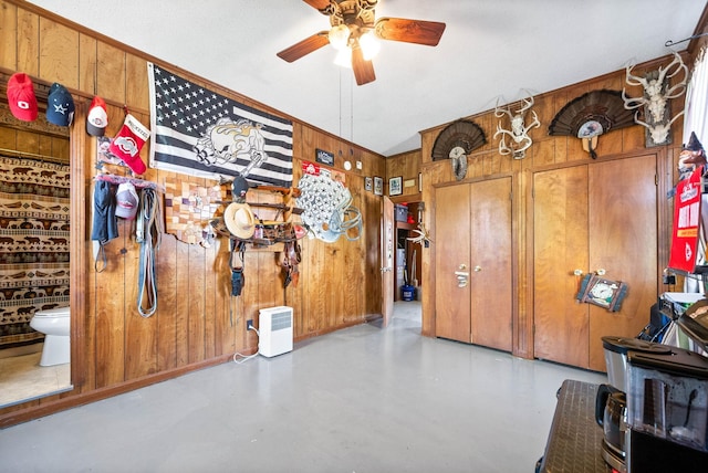 interior space featuring wooden walls, ceiling fan, and finished concrete flooring