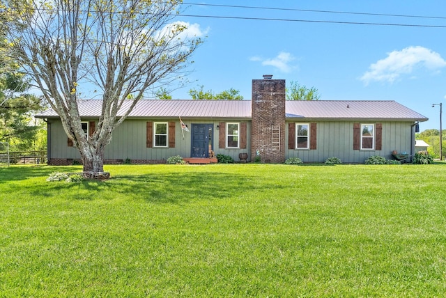 ranch-style house featuring a front lawn, board and batten siding, a chimney, and metal roof