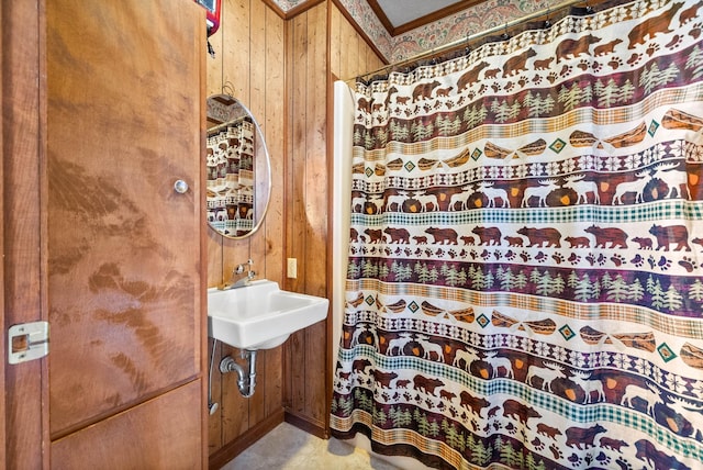 bathroom with crown molding, a shower with curtain, wood walls, and a sink