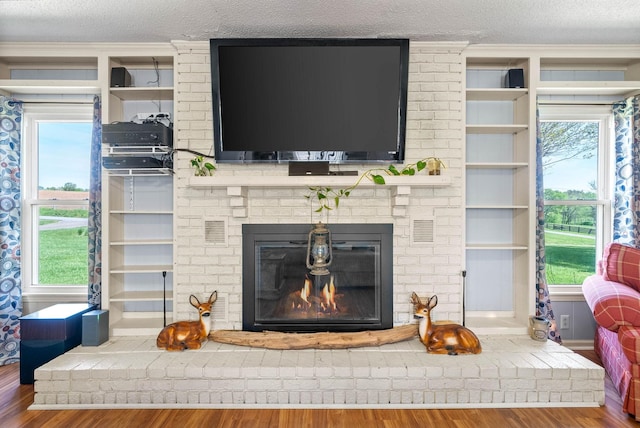 interior space featuring ornamental molding, a textured ceiling, wood finished floors, and a fireplace