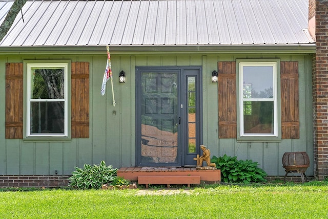 view of exterior entry featuring a lawn and metal roof