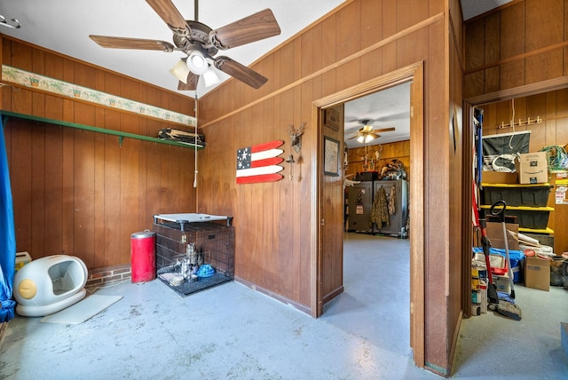miscellaneous room with a ceiling fan, concrete floors, and wooden walls